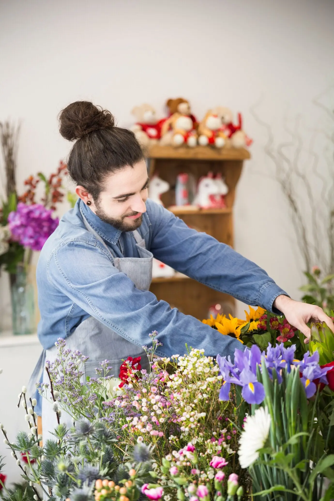 Ein männlicher Florist arrangiert die frische, bunte Blume im Laden.